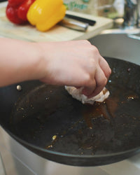 フライパンの汚れをキッチンペーパーで拭いている様子